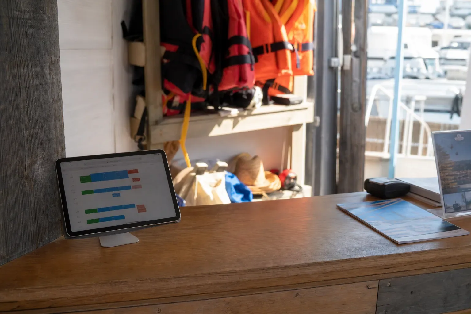 Comptoir d’accueil au bord d’un ponton d’embarquement avec une tablette affichant un calendrier de réservations
